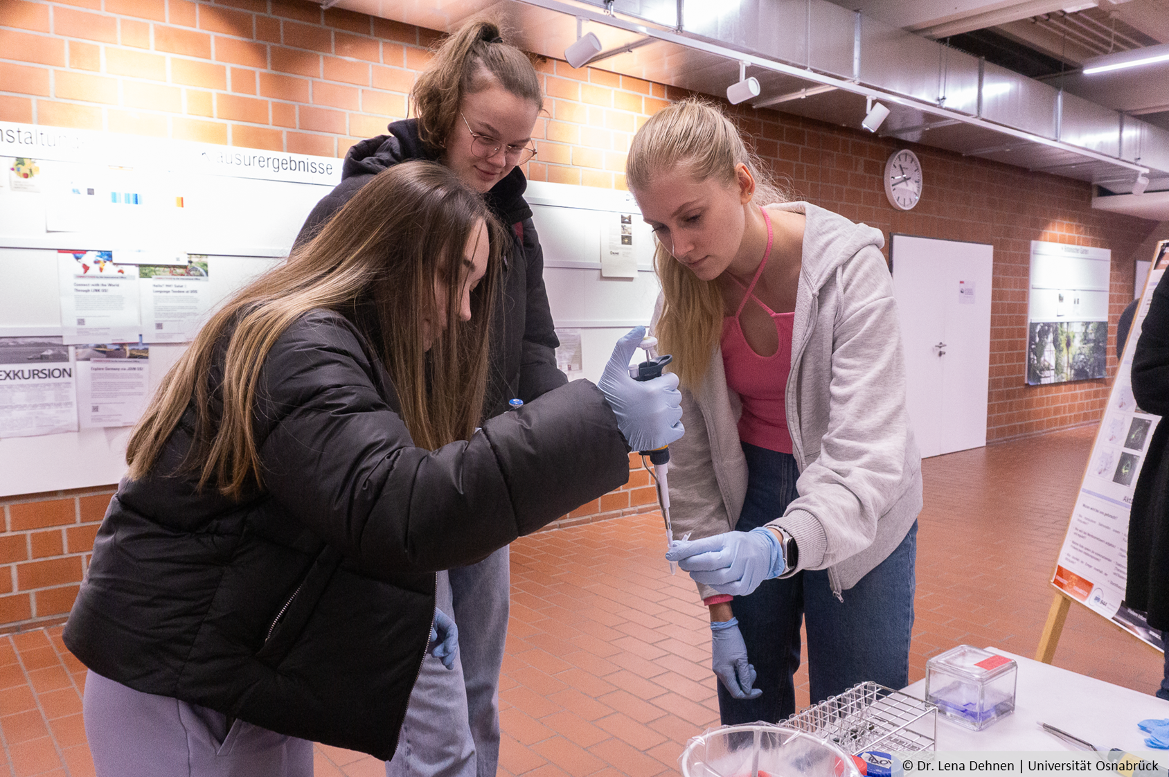 Three young people work with a pipette.