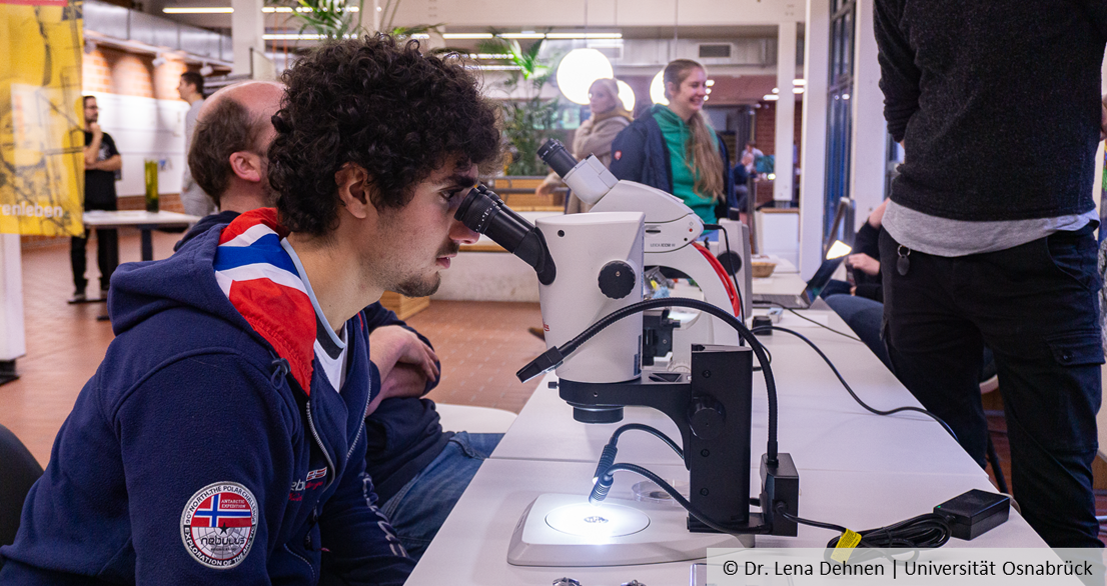 A young person looks through a microscope.