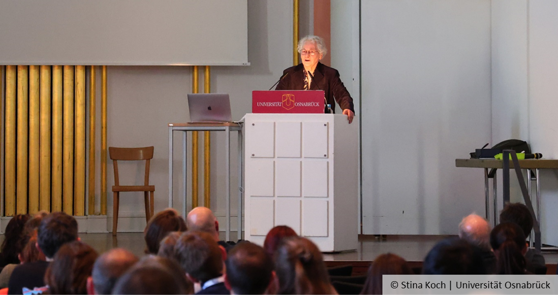 Prof. Dr. Christiane Nüsslein-Volhard steht an einem Rednerpult, im Vordergrund sind Zuhörende von hinten zu sehen.