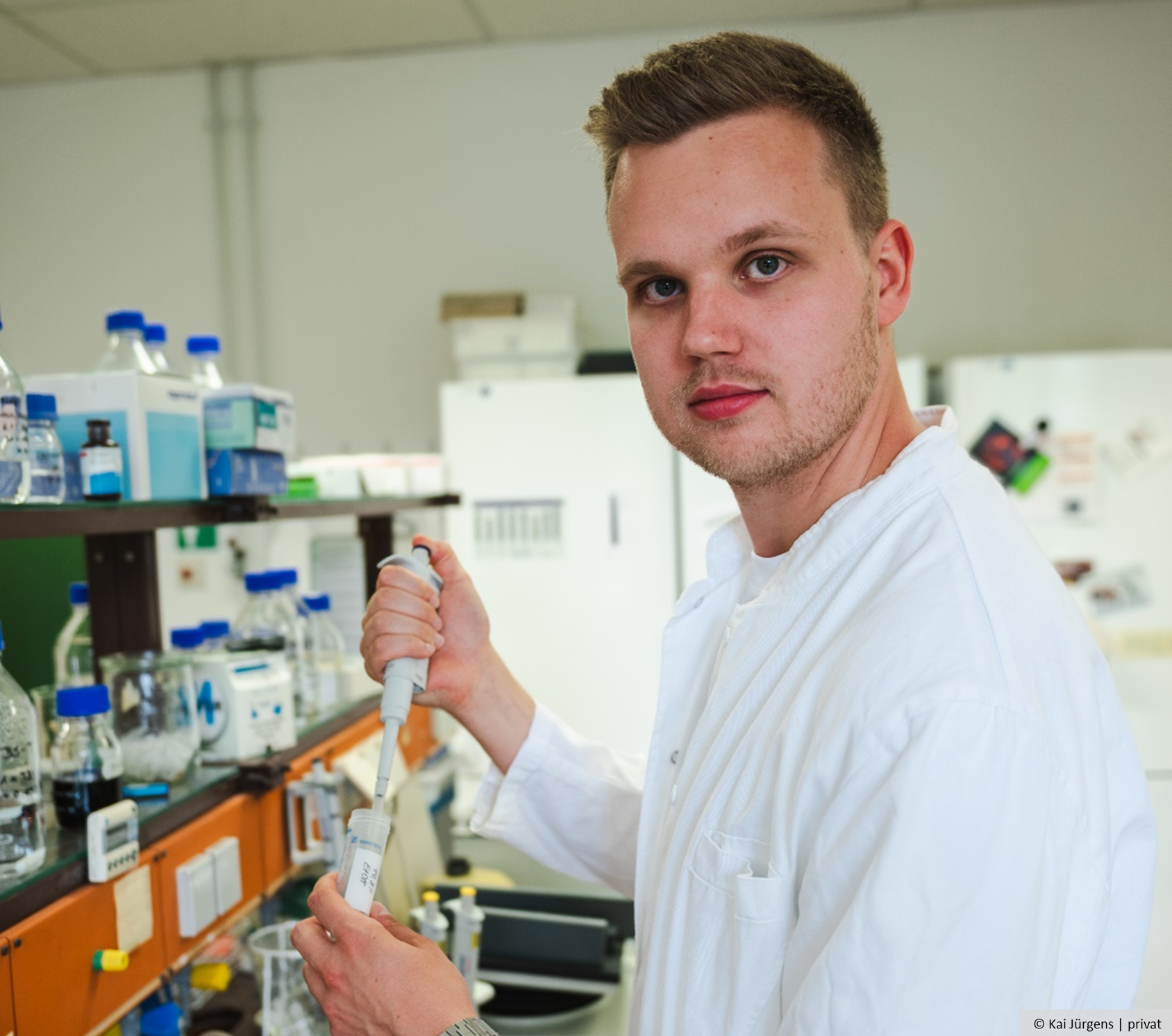 A man stands in the laboratory holding a pipette