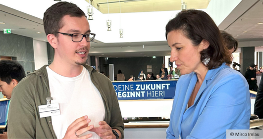 Ein Mann und eine Frau im Gespräch auf einem Messestand.